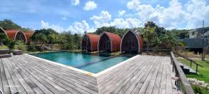 a house with a swimming pool and a wooden deck at Batu Jaran Hill Cottage & villa Lumbung Uluwatu in Uluwatu