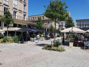a person walking through a courtyard with tables and umbrellas at "L'escapade Havraise" Studio Parking gratuit Coeur de Ville in Le Havre