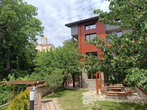 ein rotes Backsteingebäude mit einem Gebäude im Hintergrund in der Unterkunft Къща за гости Приказка in Klisura