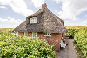 a thatch roofed house with a bench and flowers at Haus Südkap in Hörnum