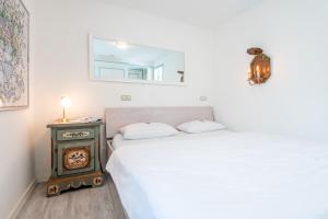a white bedroom with a bed and a stove at Haus Südkap in Hörnum