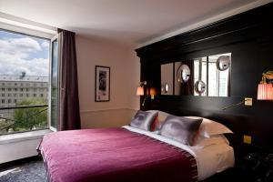 
a bedroom with a large bed and a large window at Hotel Observatoire Luxembourg in Paris
