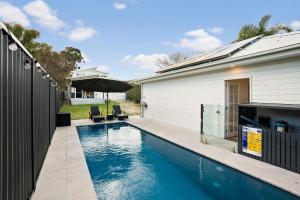 a swimming pool in front of a house at Lakeshore Serenity @ Warners Bay in Warners Bay