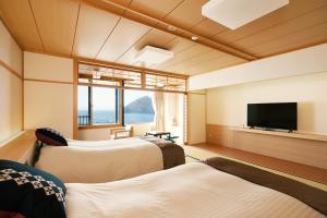 ein Zimmer mit zwei Betten und einem Flachbildfernseher in der Unterkunft Kaisenkaku in Aomori