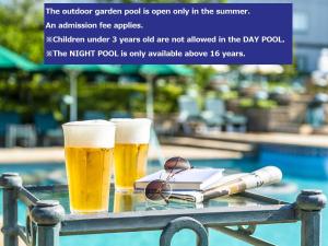 two glasses of beer on a table next to a swimming pool at Hotel East 21 Tokyo in Tokyo