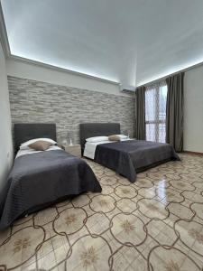 a bedroom with two beds and a brick wall at Sweet home Angi in Marsala