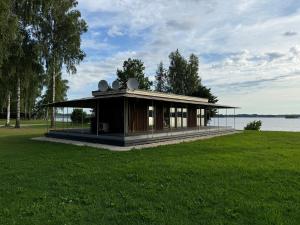 a small building in a field next to a lake at Daugavas krasti in Aizkraukle