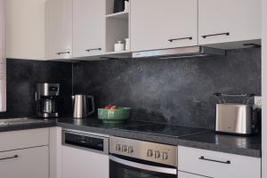 a kitchen with white cabinets and a stove top oven at Apartment A12 - zwei Bäder, Balkon & Nutzung der Gemeinschaftsräume im "Pine Hill Resort" in Zirchow