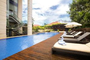 a swimming pool with chaise lounges and chairs next to a building at Fraser Residence Menteng Jakarta in Jakarta