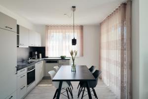 a kitchen with a table and chairs in a kitchen at Apartment A12 - zwei Bäder, Balkon & Nutzung der Gemeinschaftsräume im "Pine Hill Resort" in Zirchow
