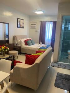 a bedroom with a bed and a couch in a room at Kral Suite in Las Piñas in Manila +29 photos