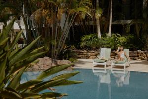 una mujer sentada en sillas junto a una piscina en The Executive Inn, Newcastle, en Newcastle