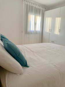 a white bed with green pillows on top of it at Cal Jan - El Monterròs in Bellver de Cerdanya +14 photos