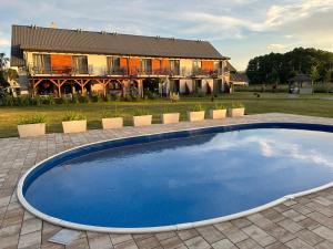 a large blue swimming pool in front of a house at Pokoje Gościnne Kameralnie in Jantar