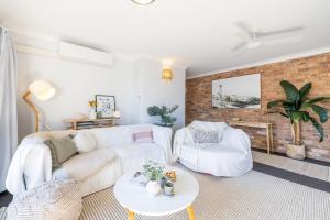 Krait Court, 6-6 Krait Close في خليج نيلسون: غرفة معيشة مع أريكة بيضاء وجدار من الطوب