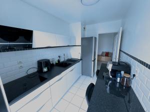a white kitchen with a sink and a refrigerator at Le Havre du Stade de France BY UTA HOUSE in Saint-Denis +12 photos