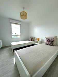a white bedroom with a large bed and a bench at Le Havre du Stade de France BY UTA HOUSE in Saint-Denis