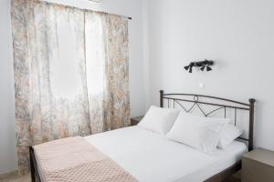 a bedroom with a bed with white sheets and a window at Harbour View Holiday Home in Ermoupoli