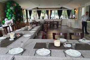 un ristorante con tavoli e sedie e un uomo in piedi sullo sfondo di Anastasija Sobe AS a Vrnjačka Banja