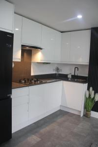 a kitchen with white cabinets and a black refrigerator at 3 Bed house walking distance to Central line in Woodford Green