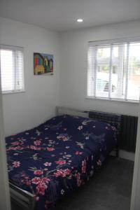 a bedroom with a bed with a blue comforter and windows at 3 Bed house walking distance to Central line in Woodford Green