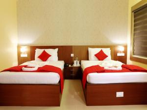a bedroom with two beds with red and white pillows at Parco Residency in Tellicherry