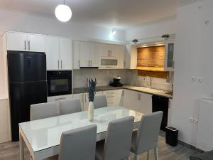 a kitchen with a white table and a black refrigerator at FOUR SEASOΝ Konstantinas in Áyios Thomás