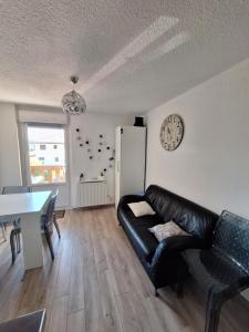 a living room with a black leather couch and a table at Studio rénové confort meublé 3 étoiles - Les Crêtets in Les Rousses