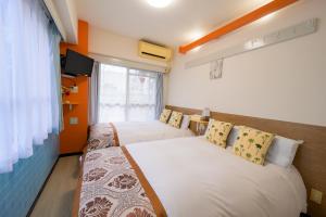a hotel room with two beds and a television at HOTEL AARON通天東 in Osaka