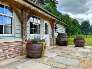 una casa con due grandi vasi di fiori su un patio di Lynford Holiday Cottages nestled in the heart of Thetford Forest a Mundford