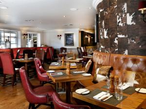 restauracja z drewnianymi stołami i skórzanymi krzesłami w obiekcie Macdonald Inchyra Hotel & Spa w mieście Falkirk