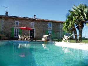 a large swimming pool with a red umbrella and a building at Franmélie in Valence en Poitoux