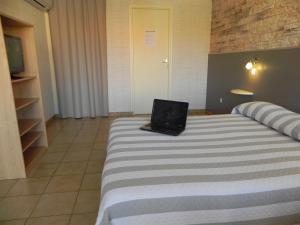 a laptop computer sitting on a bed in a room at Hotel Les Pins in Hourtin
