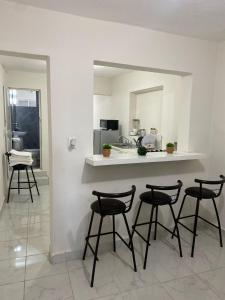 a kitchen with four bar stools and a counter with a mirror at Departamento vacacional in Mazatlán