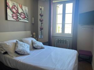a bedroom with a white bed with a window at L'Artimon by les Ambassadeurs - Saint Malo Plage in Saint Malo +4 photos