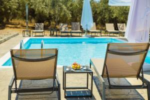 two chairs and a table in front of a swimming pool at La Perla Del Campo in Kánalos