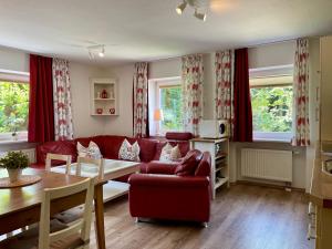 a living room with a red couch and a table at Haus Am Mühlbach - SommerBergBahn unlimited kostenlos in Oberstdorf