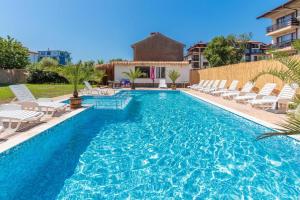a swimming pool with white chairs and a swimming pool at Хотел Черноморец in Chernomorets