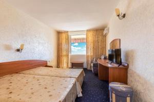 a hotel room with two beds and a television at Хотел Черноморец in Chernomorets