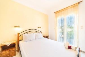 a white bedroom with a bed and a window at Olga Apartments in Agios Georgios