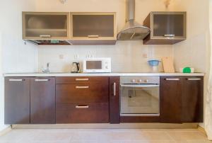 cocina con armarios de madera y microondas en Five Stars Kirova 23a, en Chelyabinsk