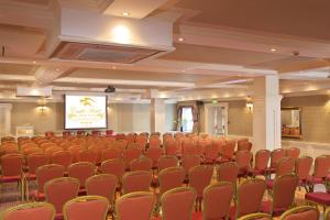 Castle Hotel Macroom في ماكروم: قاعة اجتماعات مع كراسي حمراء وشاشة