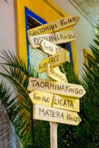 a street sign with many signs in different languages at L'Alloggio dell'Artista in Belpasso