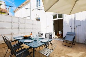 einem blauen Tisch mit Stühlen und einem Sonnenschirm auf einer Terrasse in der Unterkunft Duplex joliment décoré et sa cour ensoleillée in Saint-Martin-de-Ré