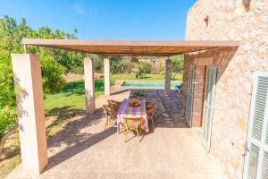 a patio with a table and chairs under a pergola at Pedra Viva -Cala Bona- in Cala Bona