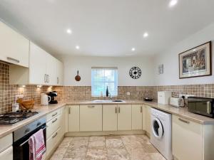 a kitchen with white cabinets and a washer and dryer at Copper Cottage in Atworth