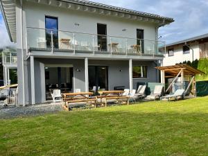 a house with a deck with chairs and tables at Mountain Chalet Top 3- mit Garten und Grill in Fieberbrunn