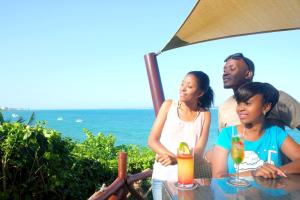 a group of people sitting at a table near the ocean at Voyager Beach Resort in Mombasa