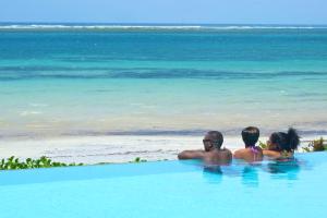 a group of people sitting in a swimming pool near the beach at Voyager Beach Resort in Mombasa
