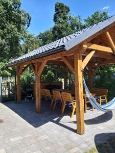 a wooden pavilion with a hammock and a table and chairs at Wypoczynkowo in Stegna